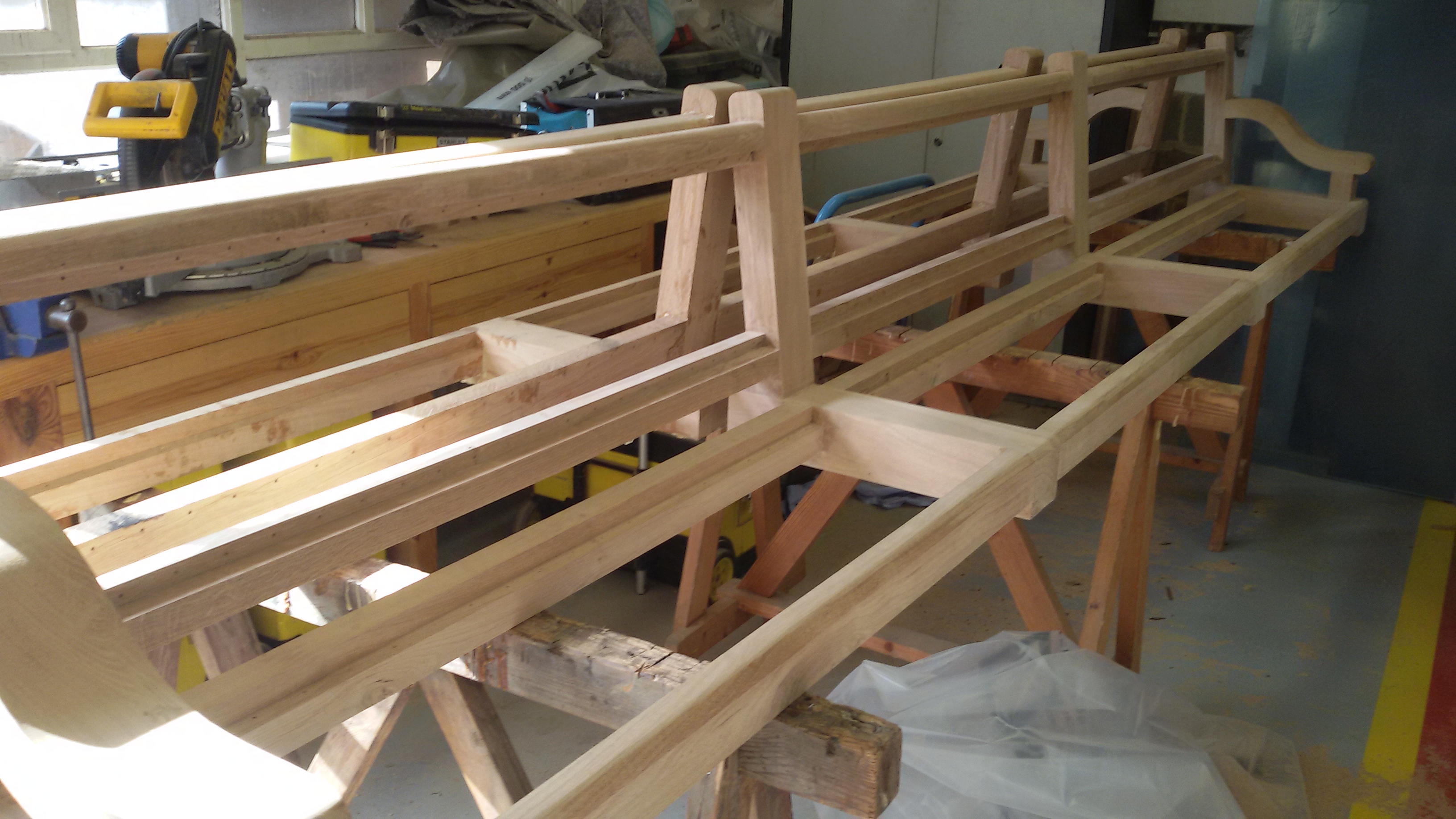 Het frame voor de houten banken opgesteld op schragen in het atelier van de schrijnwerkerij.