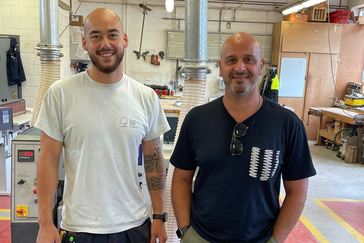 Sacha en Mehdi poseren voor de foto in het atelier van de schrijnwerkers van Leefmilieu Brussel.