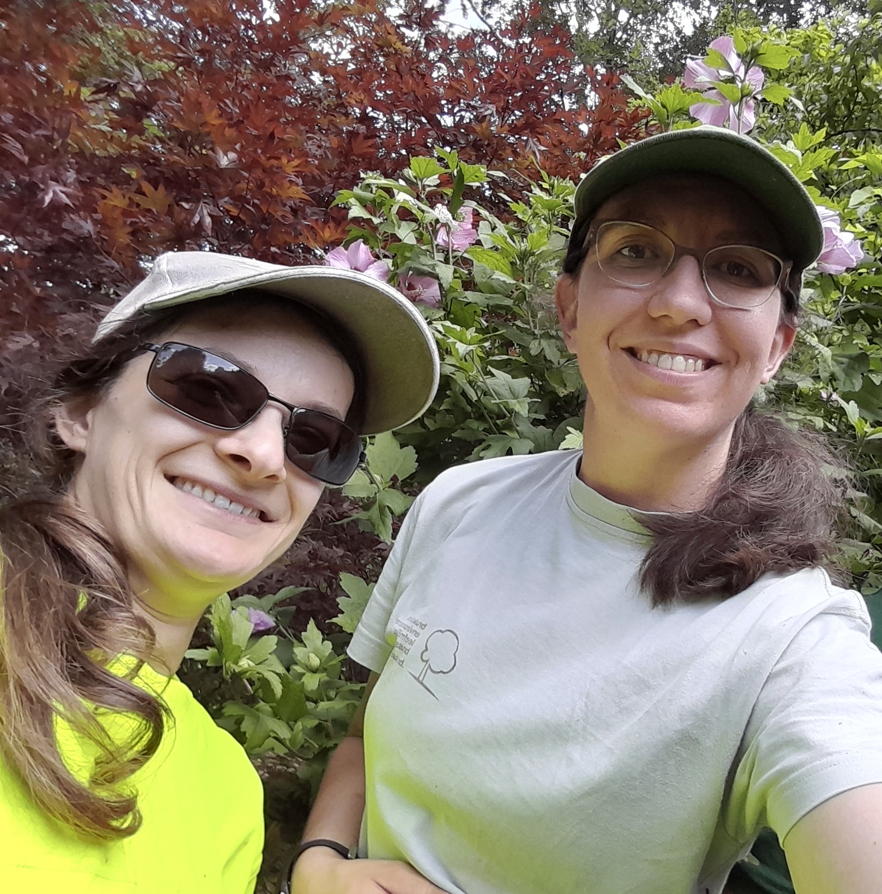 Camille en Myriam in hun werkkleding voor een groen bosje.