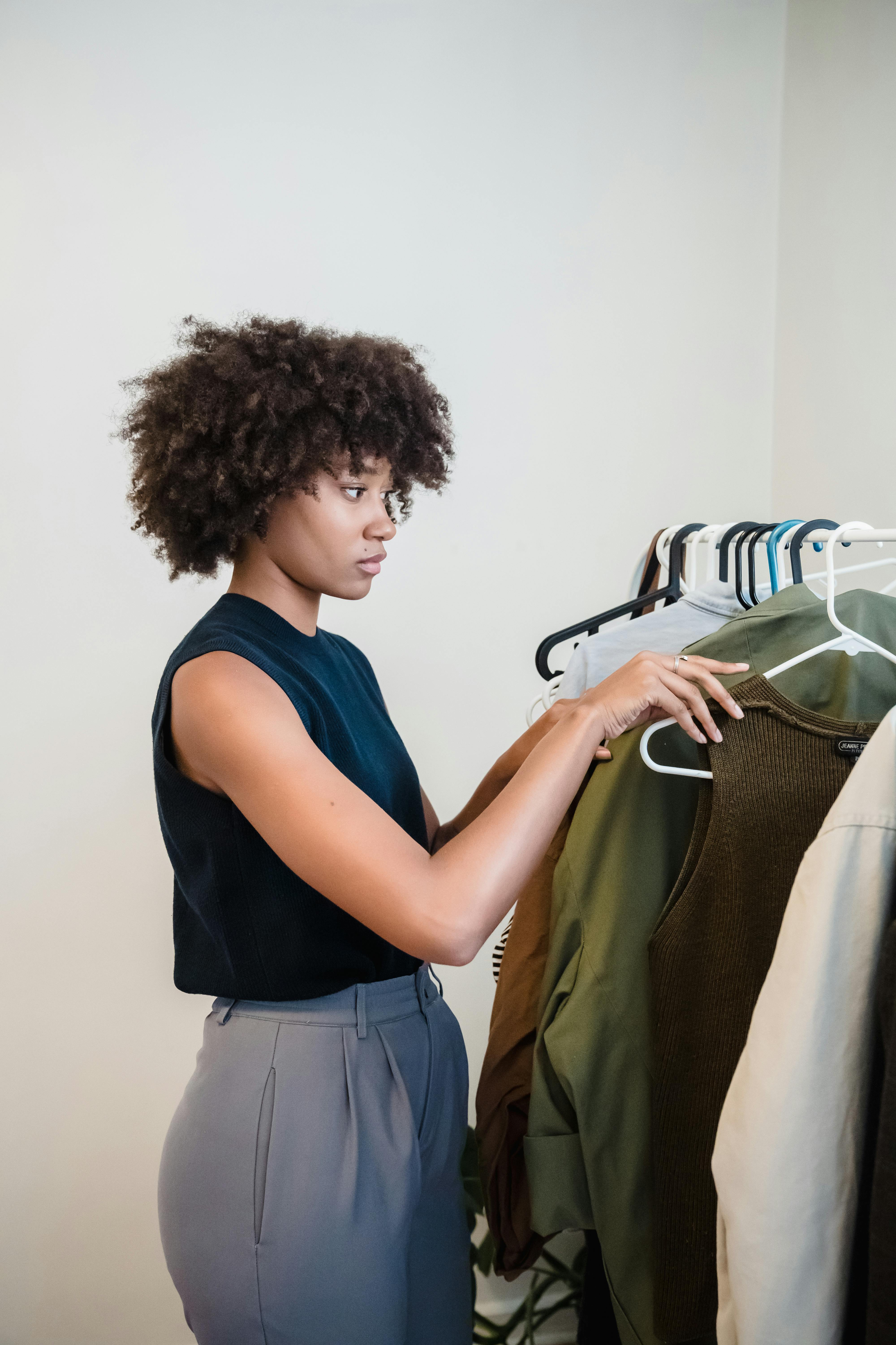 Une femme trie ses vêtements sur une tringle