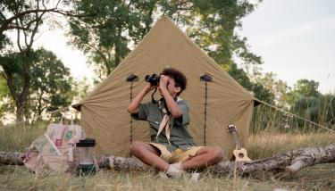 Un enfant scout assis devant sa tente 