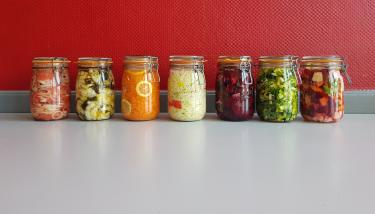 Divers pots contenant des aliments et condiments sur fond rouge