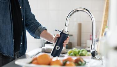 Personne qui rempli sa gourde au robinet