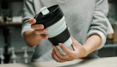 Une femme tient un mug réutilisable